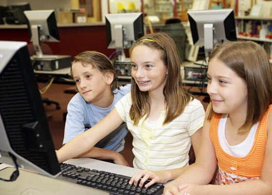 Three you ng students working together on a computer in a classroom
