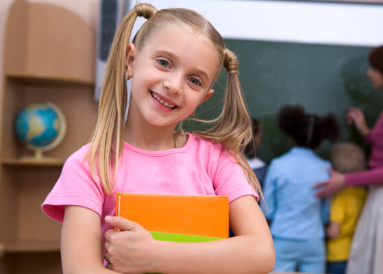 Girl smiling inside of an elementary school classroom